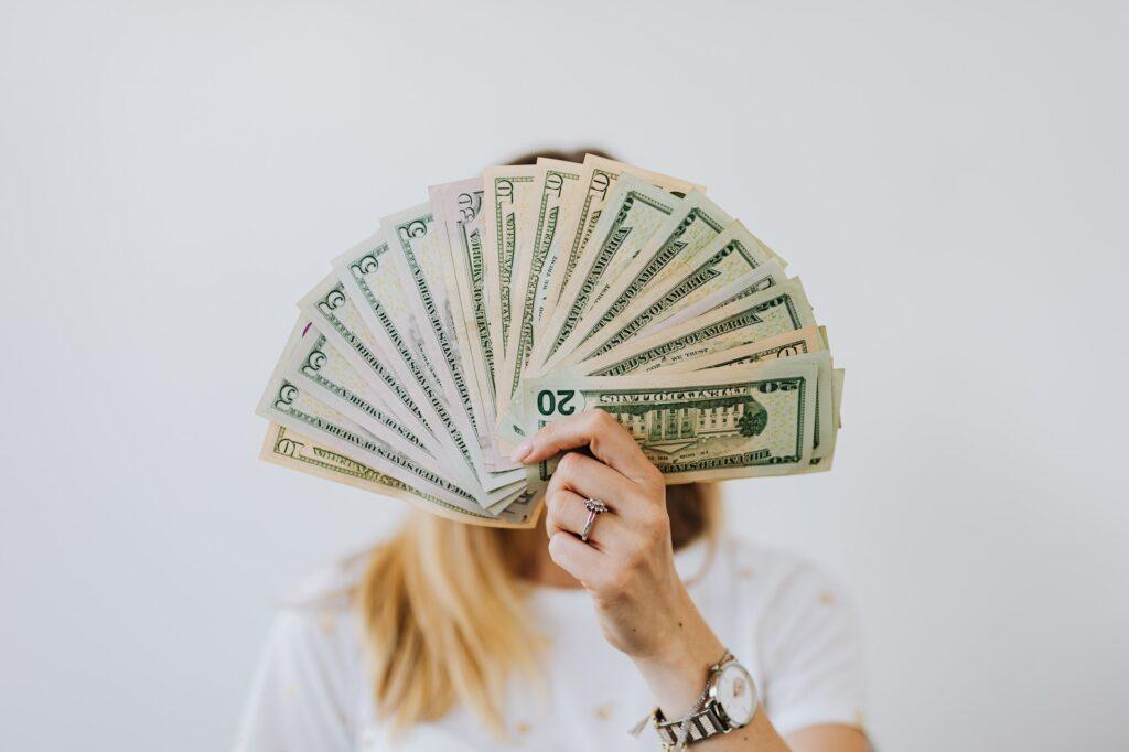 Woman holding fan of US dollar bills