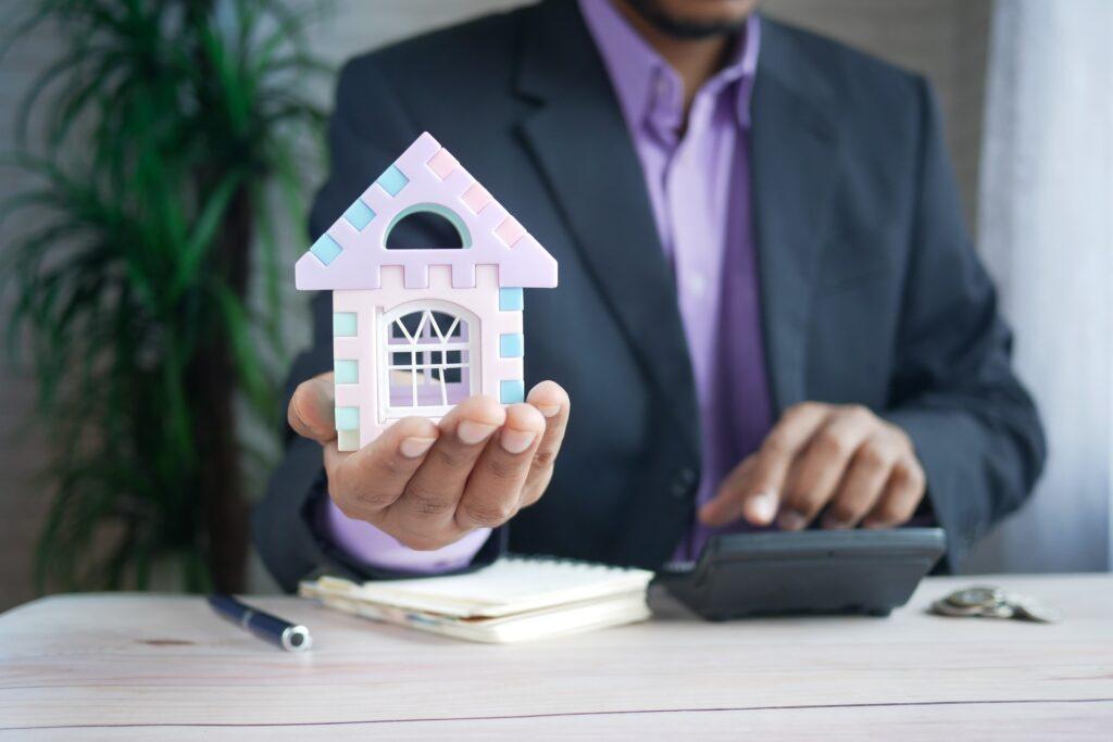 man holding miniature house