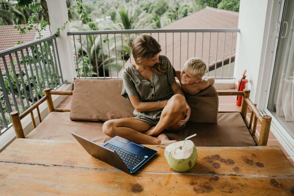 man and woman sitting on brown couch using macbook